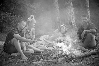Ormanda arkadaşlar kamp. İki çiftler kamp ateşi üzerinde sopalarla sosis kızartıyor. Yürüyüşçüler ormanda gece kalmak