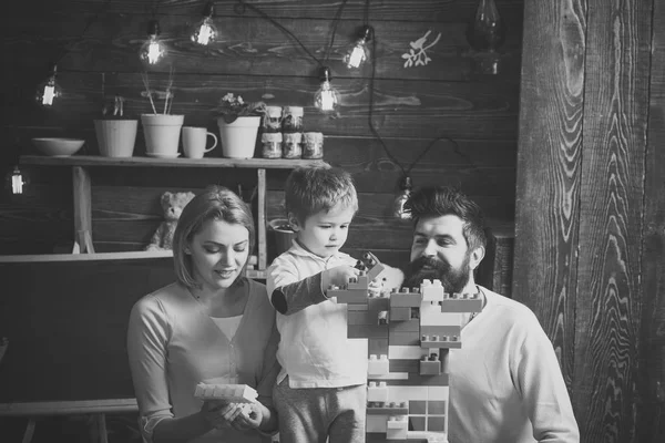 Concepto de juego educativo. Familia en la cara ocupada pasar tiempo juntos en la sala de juegos. Padre, madre e hijo lindo juegan con ladrillos constructores. Niño con los padres juegan con bloques de plástico, construir la construcción . —  Fotos de Stock