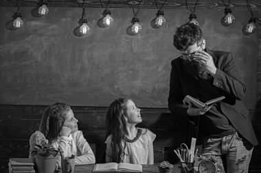 Sınıf arka planda öğretmen ve kız öğrenciler. Ev okullama ve okul konsepti geri. Gülümseyen yüzler ile çocuklar ve öğretmen. Kızlar ve sakallı adam masada oturup kitap okumak