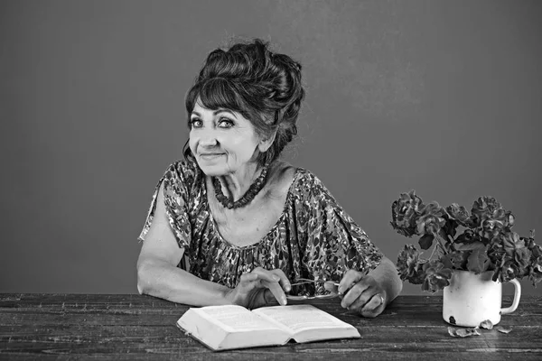 Mulher velha livro de leitura com óculos e flores — Fotografia de Stock