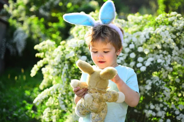 Полювання на яйця на весняні канікули. Кролик з кролячими вухами. Заєць іграшка. Маленький хлопчик у зеленому лісі. Люблю Великдень. Сімейне свято. Щасливого Великодня. Дитинство. Кукурудза, ніж будь-який кролик — стокове фото