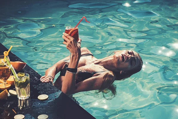 Bevi succo di vitamina fresco, dieta. Donna di moda con alcool rinfrescante a Miami. Cocktail con frutto a ragazza sexy in piscina su maldive. Vacanze estive e nuoto al mare. Festa in piscina relax in località termale . — Foto Stock