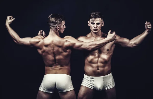 Bodybuilder tweeling met sexy gespierd lichaam. bodybuilder mannen in witte broek. — Stockfoto