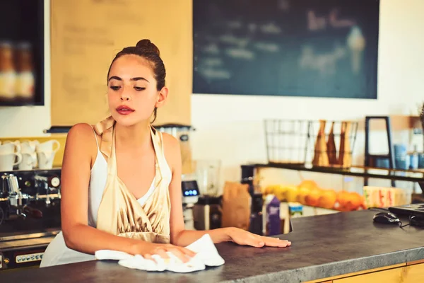 Keeping everything clean. Pretty woman stand behind cafe counter. Cute bartender or bar keeper. Barista clean counter top in bar. Woman barista in coffee shop. Serving food and drink in coffeehouse