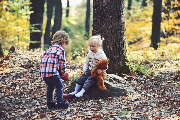 Brat siostra pomoc postawić czerwone buty. Mały chłopiec umieścić buty na stopy dziewczyny. Pomocną dłoń koncepcja. Dzieci przygotowują się do spaceru w lesie jesienią. Dzieciństwa przyjaźni, miłości i zaufania — Zdjęcie stockowe
