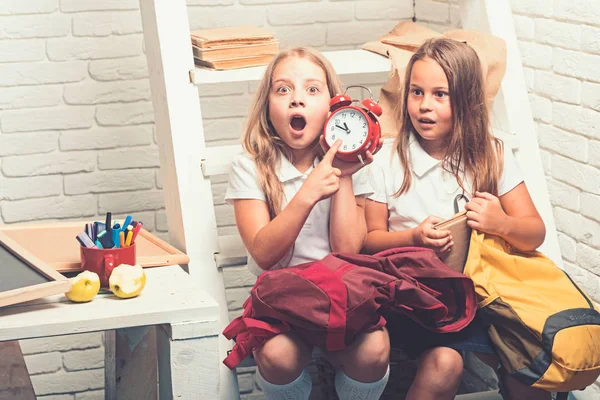 Spät. Geschockte kleine Mädchen zeigen die Uhrzeit an. Kleine Kinder zu spät zur Schule. — Stockfoto