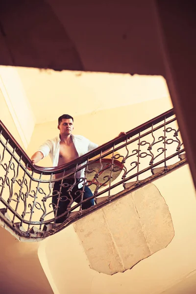 Mann steht hoch oben auf Treppe. Geschäftsleute steigen Treppen hinauf. sexy Macho im offenen Hemd mit nacktem Oberkörper auf der Treppe. Erfolg in Karriere, Ehrgeiz und Leistungskonzept — Stockfoto