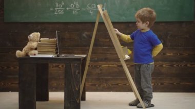 Güzel yürümeye başlayan çocuk ahşap arka plan üzerinde tebeşir üzerinde çizim. Küçük sanatçı ahşap bir arka plan üzerinde boyalar. Güzel sanatlar kavramı. Matematik okuyan zeki küçük adam. Öğrenme kavramı. Okula geri dön.