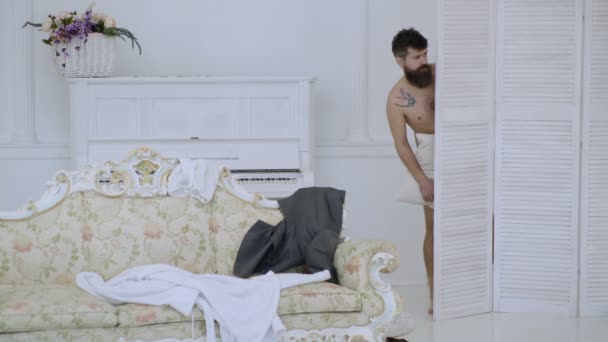 Hipster naked on shocked face unexpectedly detected in bedroom. Exposing lovers concept. Man with beard and mustache hiding behind folding screen. Man, lover in white interior caught naked. — Stock Video