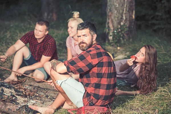 Hipster z brodą odpocząć z przyjaciółmi w lesie. Brodatego człowieka w koszulce na charakter Plaid. Turysta cieszyć Camping. Koncepcja wakacji letnich. Kemping podróżowanie i Wanderlust — Zdjęcie stockowe