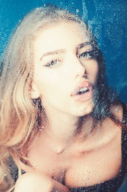 Pencere cam kız yüzü ile yağmur damlaları. Moda ve güzellik. Kız makyaj ile daha önce su ile pencere bırakır. Su ile plastik levha arkasındaki seksi kadın bırakır. Duş ve hijyen kaplıca tedavisi