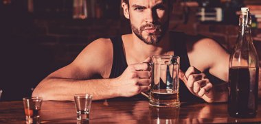 Biraz bira sahip. Bira bardağı ile alkol bağımlısı. Adam alkol barda. Yakışıklı adam içki bira bar sayacı. Bira restoran. Alkol bağımlılığı ve kötü alışkanlık. Alkollü içecek UOL