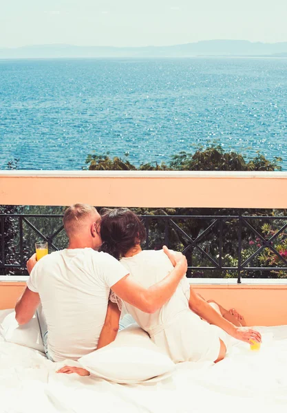 Back view retrato de um casal feliz abraçando e segurando refrescos na varanda, olhando para o mar — Fotografia de Stock