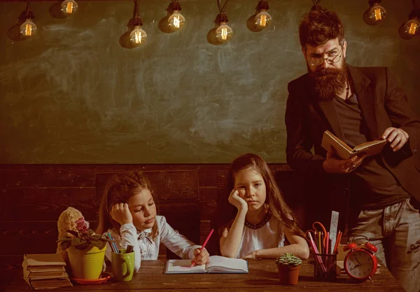 Sıkıcı ders kavramı. Öğretmen ve kız öğrencilerin sınıfta, kara tahta arka plan. Sakallı adam kız öğrenciler, kitap okuma öğretir. Bıkkın ve yorgun çocuk öğretmen dinleme.