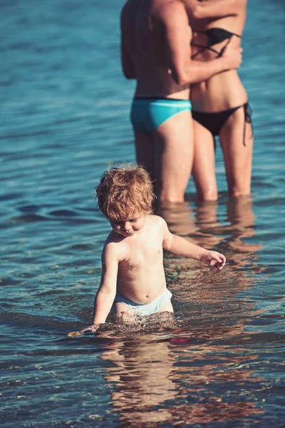 Bambino e coppia innamorati in acqua. bambino bambino nuotare in acqua di mare in estate con i genitori . — Foto Stock