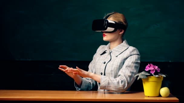 現代の教室の内部背景にラップトップ上のコンピュータプログラムを管理するためのマスク仮想現実を使用して女性。VRヘッドセットメガネデバイス。黒板の背景。学校や教育の概念. — ストック動画