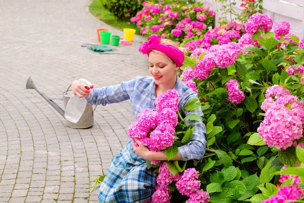 Blumenpflege und Bewässerung. Böden und Dünger. Frau pflegt Blumen im Garten. Gewächshausblumen. Hortensien. Frühling und Sommer. glückliche Gärtnerin mit Blumen. Fröhlicher Bauer im Gewächshaus — Stockfoto