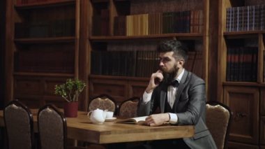 Kütüphane dolabında eski tarzda eski ahşap masa üzerinde kütüphanede kitap okuyan adam portresi. Zeki adamlar, bilim adamları boş zamanlarını kütüphanede geçirirler. Akıllı elit ve eğitim kavramı.