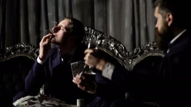 Girişimci zarif kanepe oturur ve para sayar. Broker zengin görünüyor. Alkol, zengin yaşam tarzı, iş, para kavramı. Kendine güvenen yüzü olan sakallı adam ya da beyefendi şampanya bardağı tutar.