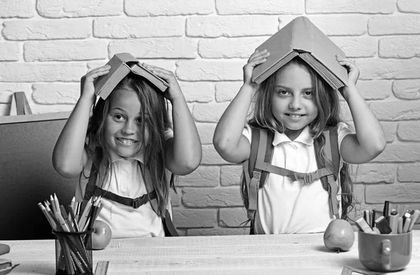 欢快的微笑的小女孩与书籍在头上。看着相机。学校概念。返回学校. — 图库照片