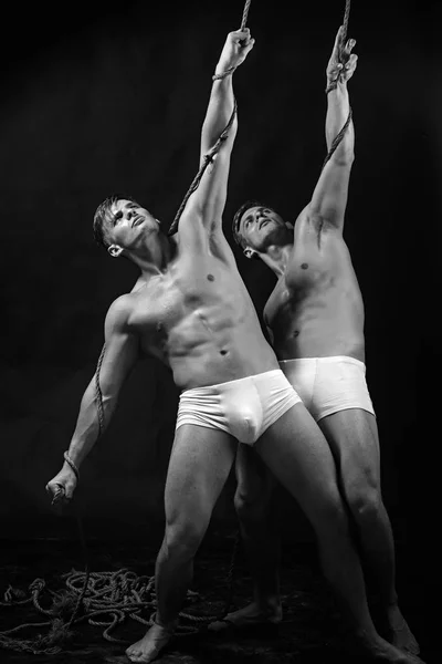 two gymnastic acrobatic caucasian men twins in same pose.