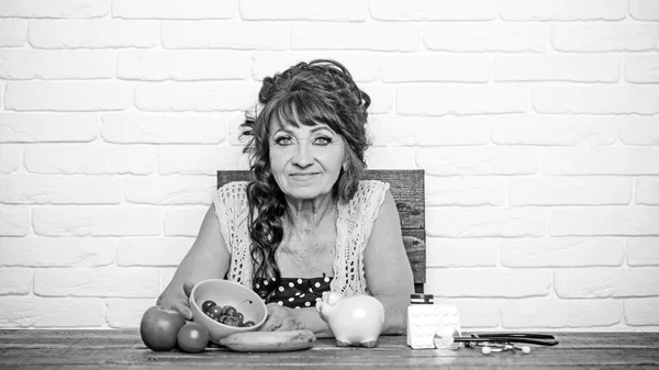 Senior vrouw met spaarvarken, fruit, geneeskunde, stethoscoop aan tafel — Stockfoto