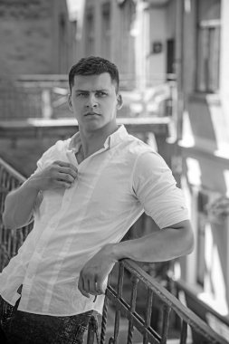 Yakışıklı genç adam balkon Küpeşte ayakta ve uzağa bakarak açık