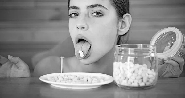 Doce dente. Menina doce com doces doces. Uma mulher bonita segura marshmallows na língua. Mulher engraçada gosta de comer marshmallows. Comida de plástico. Alimentos insalubres e prejudiciais. Lanche doce — Fotografia de Stock