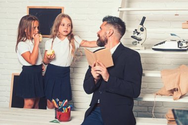 Öğretmen adam kızlar yeme elma için hikaye okuyun. Kız ve baba Kitaplığı'nda okul zamanı. Bilgi gün eğitimde. Edebiyat ders ve okuma gramer kitabı. Geri okul ve ev okullaşma