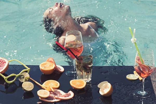 Vrouw ontspannen bij het zwembad met cocktails. — Stockfoto