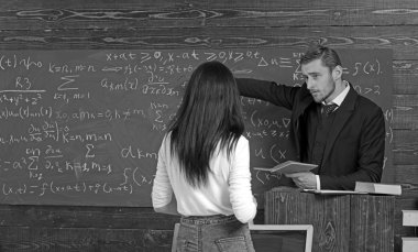 Matematik öğretmeni yeşil tahta at işaret. Esmer kız öğrenci için açıklamalar veren Profesör. Geri olarak beyaz jumper kürsü önünde duran kız çevirmek