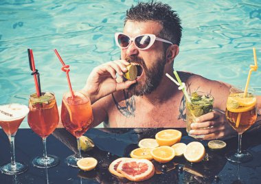 Deniz ve spa resort sakin ol. Havuzda sakallı adam meyve kokteyli. Havuz partisi, vitamin ve diyet. Adam yüzme ve içecek alkol. Miami veya Maldivler tatil yaz.