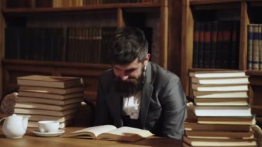 Olgun erkek yüz yorgun ve overworked görünüyor. Adam ile pek çok kitap masada oturur. Adam aşırı ve masada yatıyor. Gece çalışma, eğitim, zor iş, fikri eser, beyin, stres kavramı.