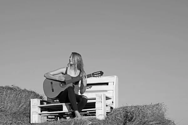 Muziek vrouw spelen gitaar op houten bankje op blauwe hemel. Muziek, vrouw gitarist uitvoeren concert op akoestische gitaar. — Stockfoto