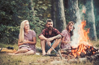 Gülümseyen arkadaşlar geçen yaz günlerini dışarıda geçiriyorlar. Kamp ateşinin etrafında oturan gençler. Çimenlerin üzerinde otururken kitap okuyan kızlar