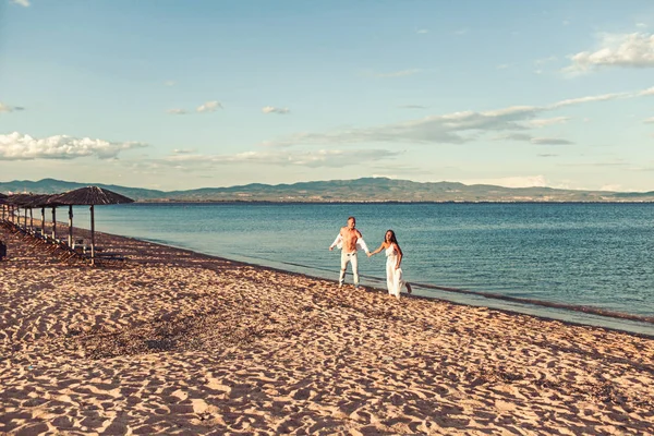 Gün batımında kumlu bir plajda koşan çift. — Stok fotoğraf