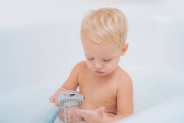 Köpükle oynayan sevimli çocuk. Sevimli sarışın yürümeye başlayan çocuk küvette banyo alarak su ile eğlenmek.