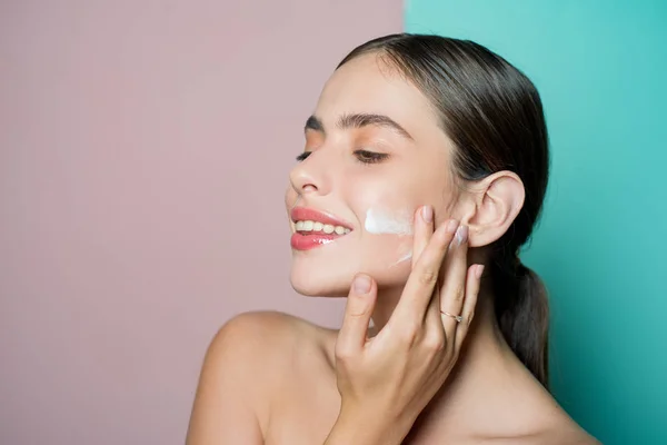 Cuidados faciais para a mulher. Mantenha a pele hidratada creme regularmente hidratante. Conceito de pele fresca e saudável. A cuidar bem da pele dela. Mulher bonita espalhando creme em seu rosto. Conceito de creme de pele — Fotografia de Stock