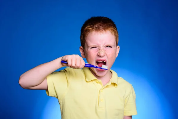 Adorable little boy holding toothbrush and smiling at camera. Mockup, free spase. Cute funny boy with a toothbrush. Dental concept - smiling teenage girl in blank white shirt brushing her teeth. — Stock Photo, Image