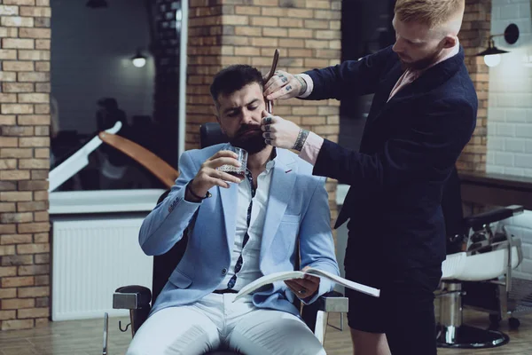 Peluquero profesional en barbería interior. Cliente masculino que se corta el pelo por peluquero. Bálsamo en partes secas del cuerpo para hidratar la piel. Corte de estilo barba. Ideas sobre Peluquería y Peluquería . —  Fotos de Stock