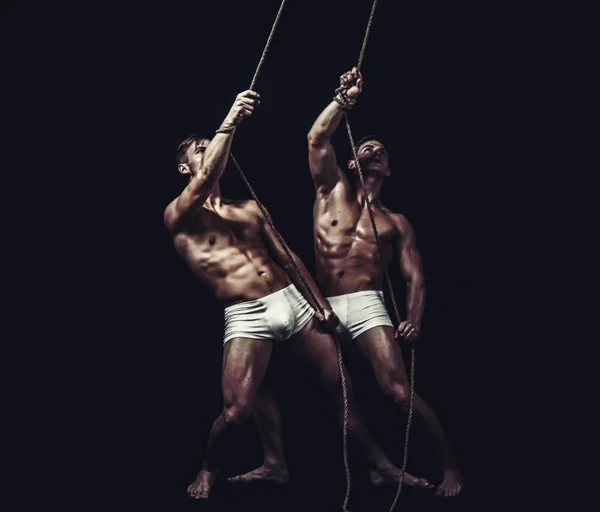 Sport training voor de bodybuilder. Fitness dieet en flexibiliteit acrobatiek. Vriendschap van mannen doen gymnastiek. Twins mannen met gespierd lichaam op touw. Circus gymnasten op pilates of yoga opleiding — Stockfoto