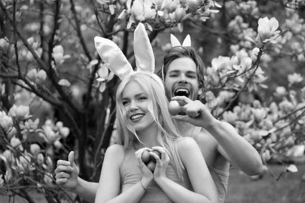 Menina e bonito homem com orelhas de coelho segurando ovos — Fotografia de Stock