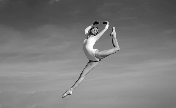 Похоже на полет. Молодая балерина прыгает на голубом небе. Красивая девушка в танцевальной одежде. Милый балетный танцор. Концертный танец. Практикует искусство классического балета. Класс балета. Классический стиль — стоковое фото