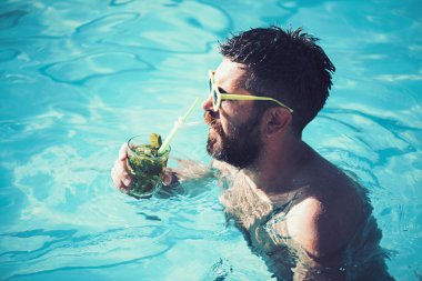 mutlu adam dinlenmek ve swimmin havuzda yaz tatilinde kokteyl almak.