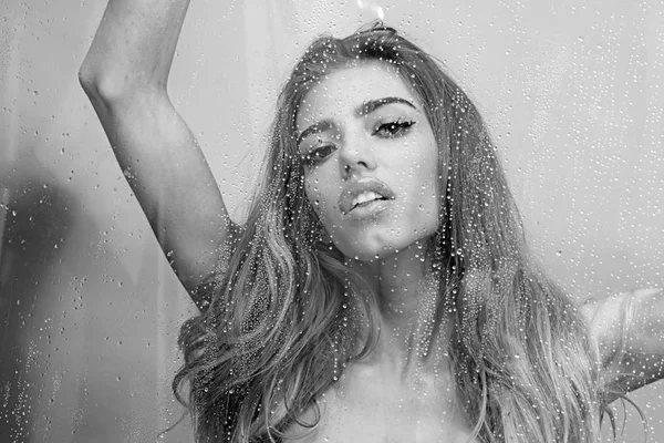 Young beautiful woman in shower. Behind wet glass window with water drops. Focus on droplets. Girl bathing, washing hair and taking fresh bath — Stock Photo, Image