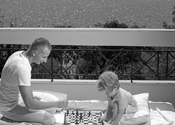 Family travel with kid on fathers day. Summer vacation of happy family. Child play chess with father. father with son on balcony play chess. Love and trust as family values.