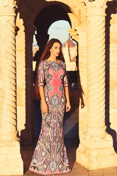 Красивая женщина в длинном платье позирует возле древней колонны. Прекрасная архитектура . — стоковое фото
