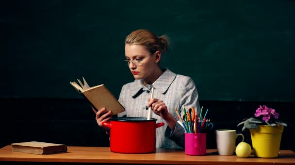 Attraktive Frau kocht. Porträt einer jungen Frau beim Kochen mit Bezug auf das Buch isoliert auf grünem Brett. Kochfrau im Klassenzimmer mit Kochlöffel. Konzept des Kochens und der Zubereitung von leckerem Essen — Stockvideo