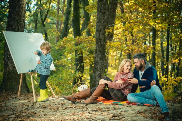 Talent development. Painting skills. Mom and dad relax park picnic while kid painting. Rest and hobby concept. Parents relaxing while their son painting picture in nature. Art and self expression
