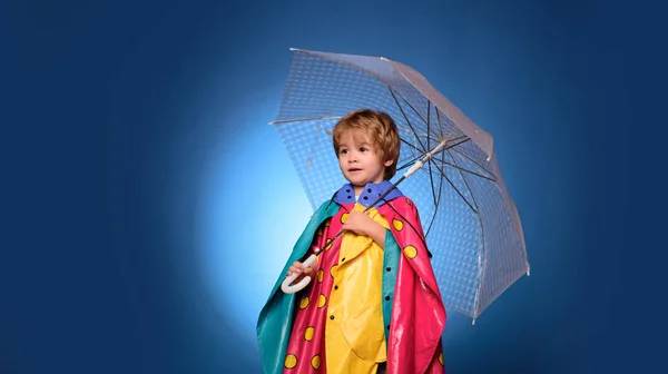 Dítě inzerují váš produkt a služby. Veselý chlapec v pláštěnku s barevným deštníkem. Podzimní koncept. Malý roztomilá chlapeček se na podzim připraví. Děti prší. — Stock fotografie